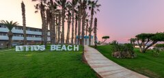 Cestička vedoucí k palmám a nápisu Lyttos Beach při západu slunce
