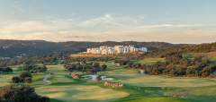 Golfové hřiště s budovami na pozadí a kopci