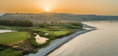 Golfové hřiště u moře s pískovým bunkrem a věží v pozadí