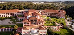 Budova hotelu s červenou střechou a zelený golfový trávník