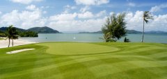 Golfové hřiště u moře s palmami a kopci v pozadí