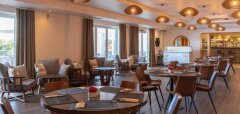 Interiér restaurace s kulatými stoly a židlemi u oken