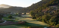 Golfové hřiště s fairway, stromy a kopci v pozadí