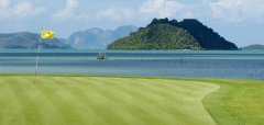 Golfové hřiště s vlajkou u moře a ostrovem v pozadí