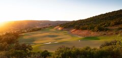 Golfové hřiště při západu slunce s kopci a stromy