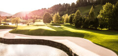 Golfové hřiště s pískovým bunkrem a jezírkem za slunečného dne