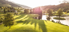 Golfové hřiště s jezírkem a stromy v horské krajině
