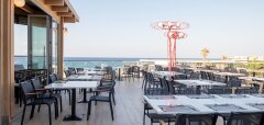 Terasa restaurace s výhledem na moře a prázdné stoly s židlemi