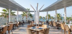 Venkovní restaurace s výhledem na moře a palmami Lyttos Beach