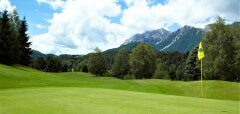 Golfové hřiště s vlajkou a horským pozadím