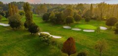 Golfové hřiště s pískovými bunkry a stromy za soumraku