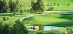Golfové hřiště s jezírkem a lesem v pozadí