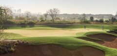 Golfové hřiště s hráči a pískovými bunkry za svítání