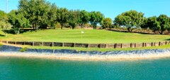 Golfové hřiště s vodní překážkou a vlajkou na greenu