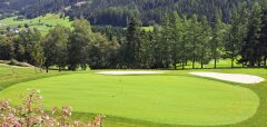 Golfové hřiště s greenem, bunkry a horským pozadím