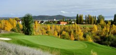 Golfové hřiště s podzimními stromy a vesnicí v pozadí
