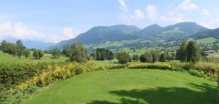Zelené golfové hřiště s výhledem na kopce a modrou oblohu
