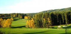 Golfové hřiště s jezírkem a podzimními stromy v pozadí