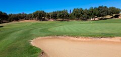 Golfové hřiště s pískovým bunkrem a zelení za slunečného dne