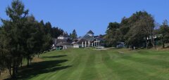 Zelené golfové hřiště s budovou a stromy na pozadí