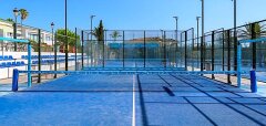 Modré hřiště na padel s oplocením a tribunou v pozadí