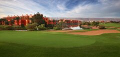 Golfové hřiště s jezírkem a oranžovými budovami v pozadí