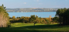 Golfové hřiště s výhledem na jezero a lesy v pozadí