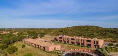 Budovy resortu s bazénem a zelenou krajinou kolem