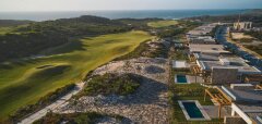 Pohled na golfové hřiště a moderní vily u oceánu při západu slunce