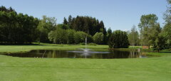 Golfové hřiště s jezírkem a fontánou za zeleným trávníkem
