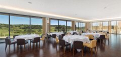 Restaurace s výhledem na golfové hřiště a stoly s bílými ubrusy