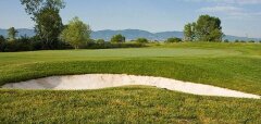 Golfové hřiště s pískovým bunkrem a zelení za ním