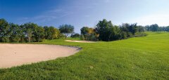 Golfové hřiště s pískovým bunkrem a zelení v pozadí