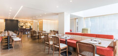 Interiér restaurace s dřevěnými židlemi a červenými lavicemi