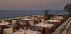 Terasa restaurace s posezením a výhledem na moře při západu slunce