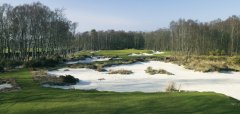 Golfové hřiště s pískovými bunkry a stromy v pozadí