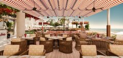 Venkovní restaurace s pruhovaným stíněním a výhledem na pláž