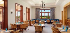 Interiér restaurace s dřevěným nábytkem a výhledem na golfové hřiště