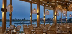 Venkovní restaurace s ratanovým nábytkem u vody za soumraku