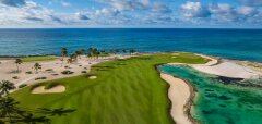 Golfové hřiště u oceánu s palmami a modrou oblohou