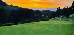 Golfové hřiště při západu slunce s kopci v pozadí