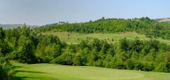 Zelené golfové hřiště obklopené stromy a kopci