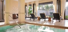 Interiér hotelového wellness s vířivkou a lehátky u velkých oken