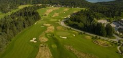 Letecký pohled na golfové hřiště obklopené lesy a kopci