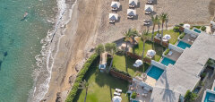 Pohled na pláž s lehátky a resort s bazény u moře