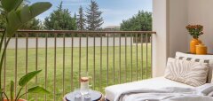 Balkon s lehátkem, stolkem a výhledem na trávník a stromy