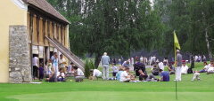 Lidé odpočívají a hrají golf u staré budovy a zeleně