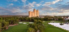 Golfové hřiště s jezírkem a vysokou budovou v pozadí