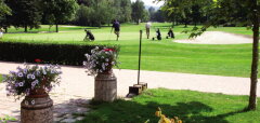 Golfové hřiště s hráči a květinami v popředí