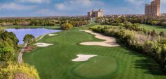 Golfové hřiště s jezírkem a budovami v pozadí
